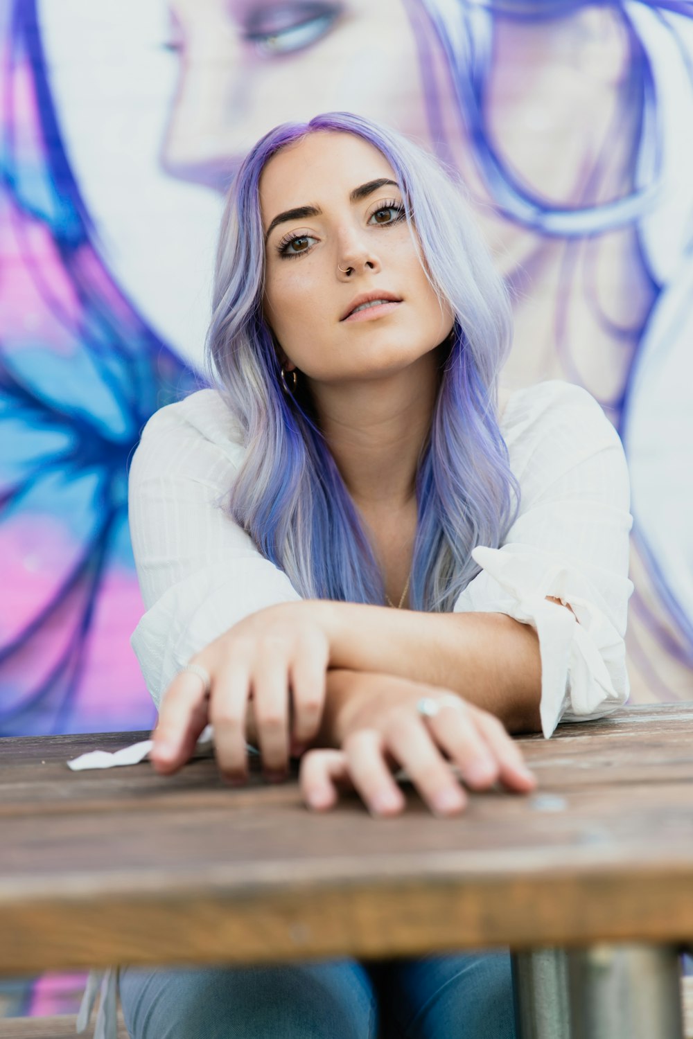 woman in white long sleeve shirt leaning on brown wooden table