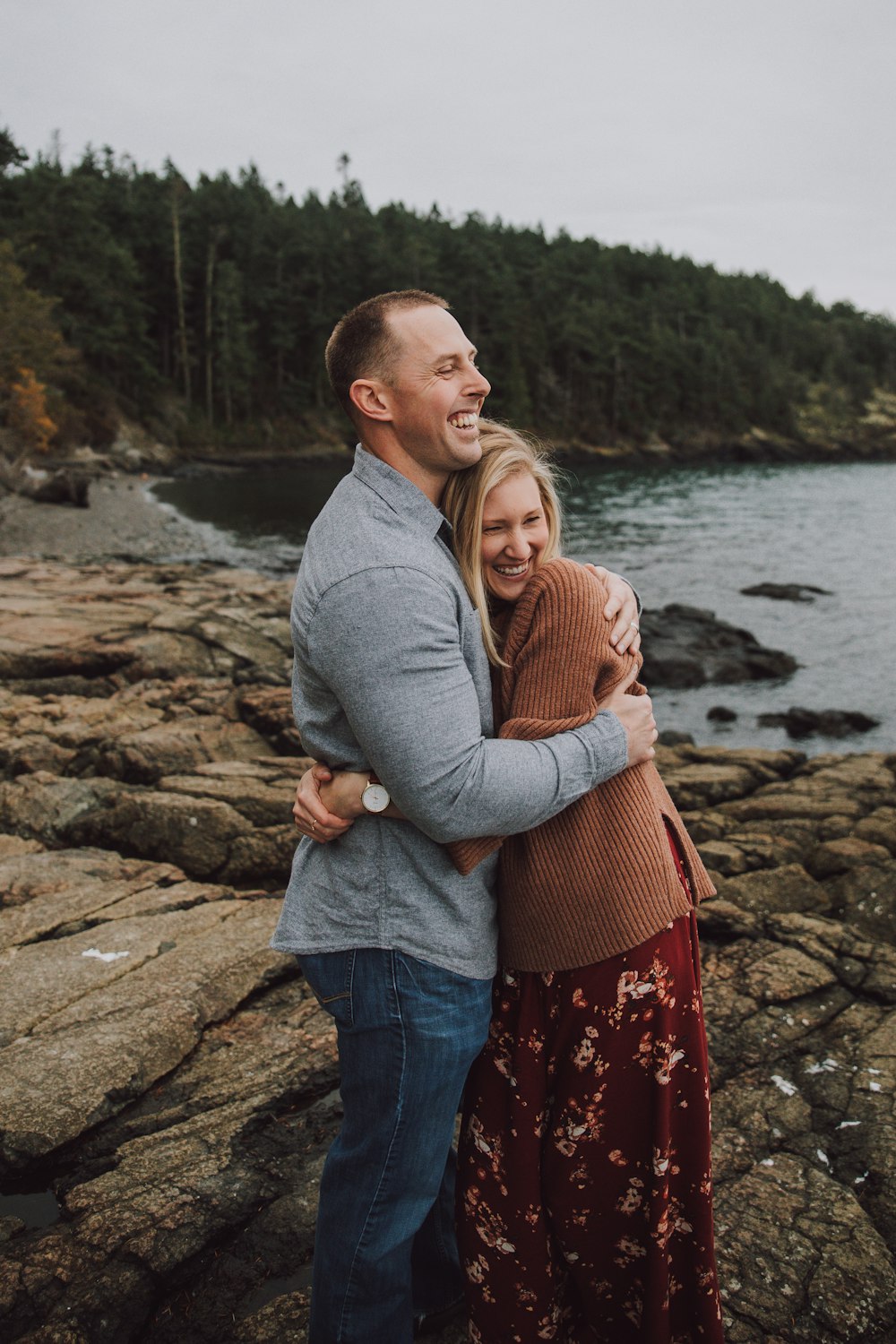 man and woman standing on rock near body of water during daytime