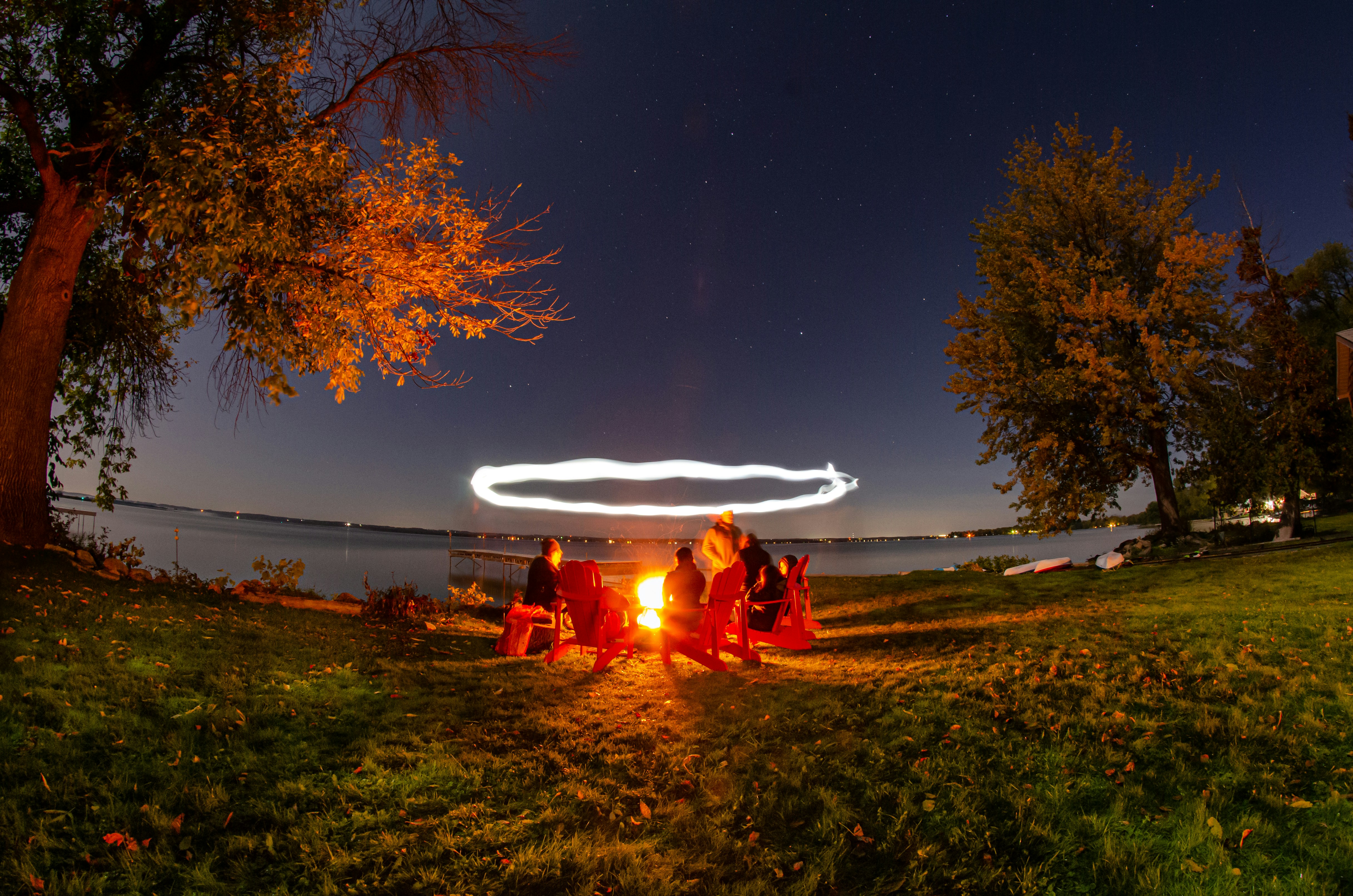 people sitting on grass field near bonfire during night time