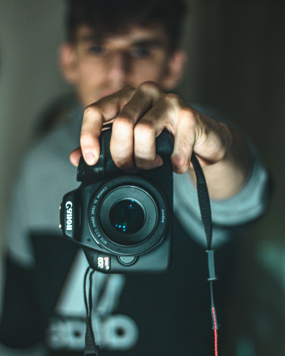 man in blue crew neck shirt holding black nikon dslr camera