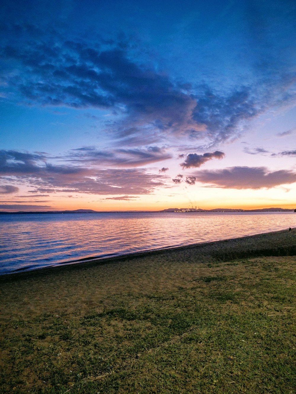 green grass field near body of water during sunset