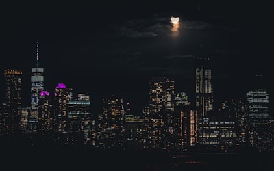 A sleek nighttime city skyline with glowing university campuses illuminated under a deep purple sky.