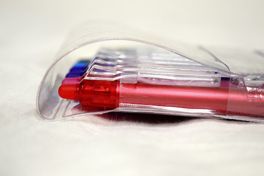 Several colorful pens encased in a clear plastic packaging, primarily showcasing a red pen in the forefront.