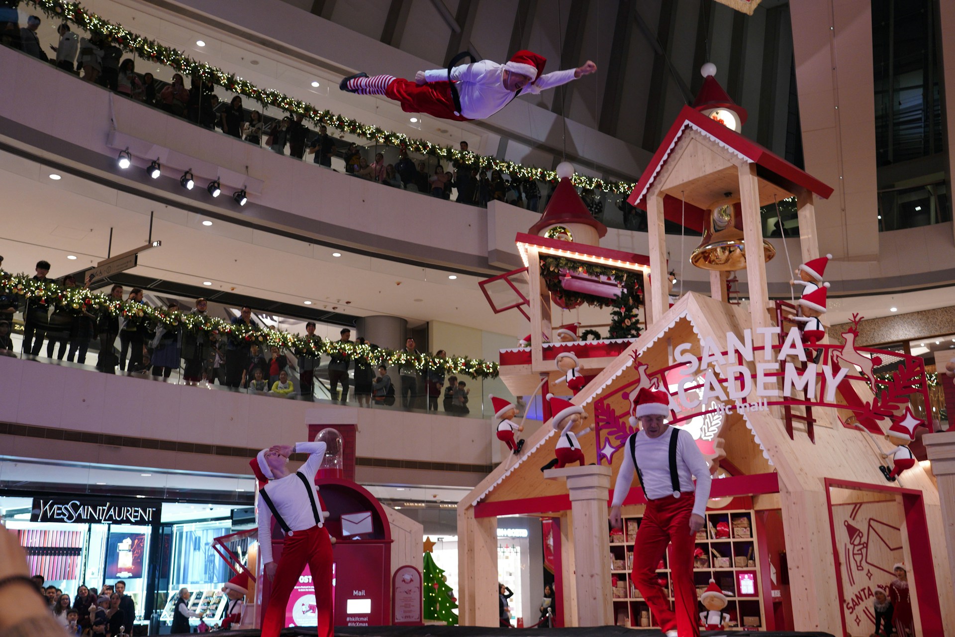 A cheerful Santa Claus performing at a festive event, surrounded by children and holiday decorations.