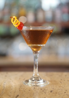 Close-up of a signature golden cocktail with a twist of citrus, resting on the black marble bar
