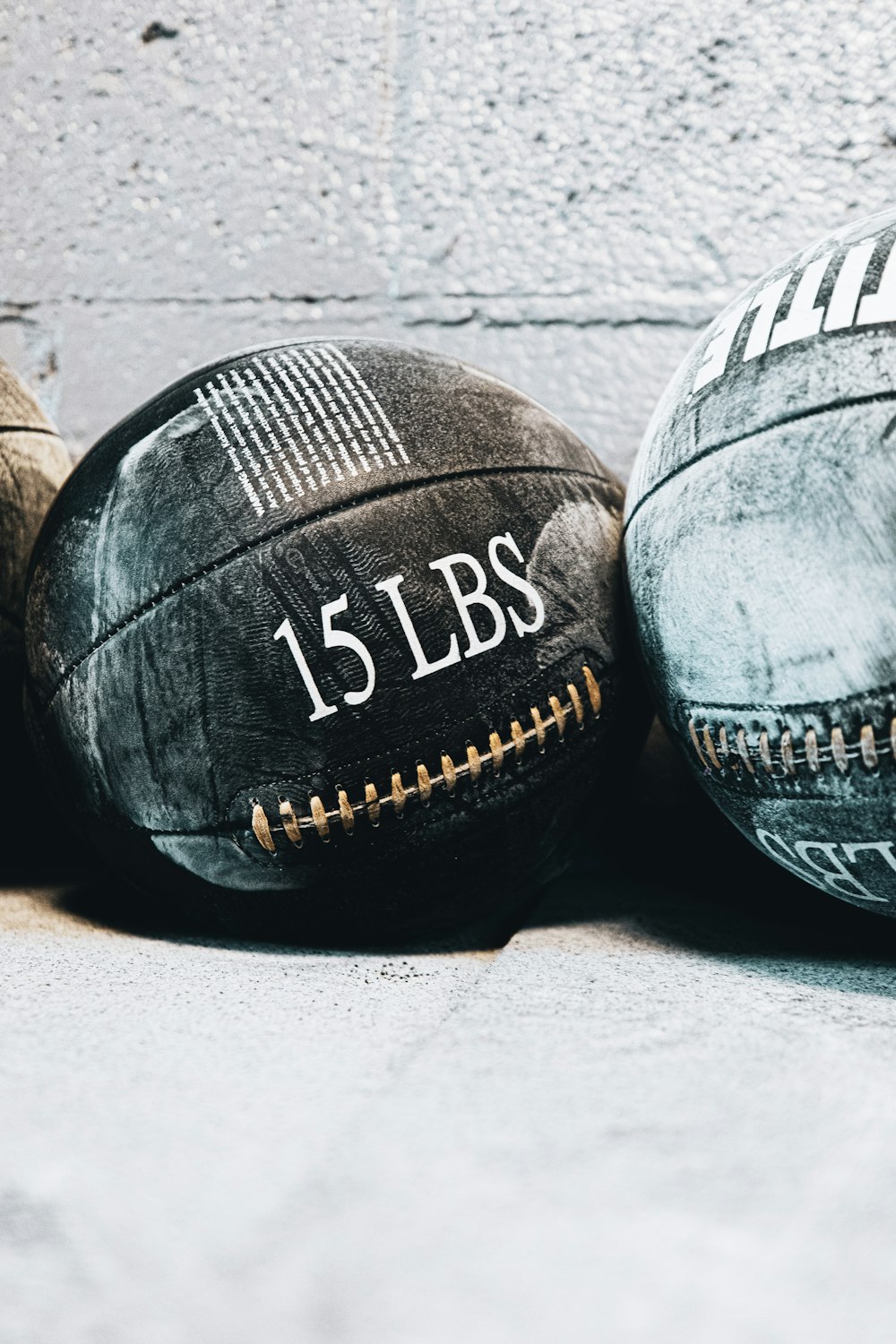 three old worn out baseballs sitting on the ground