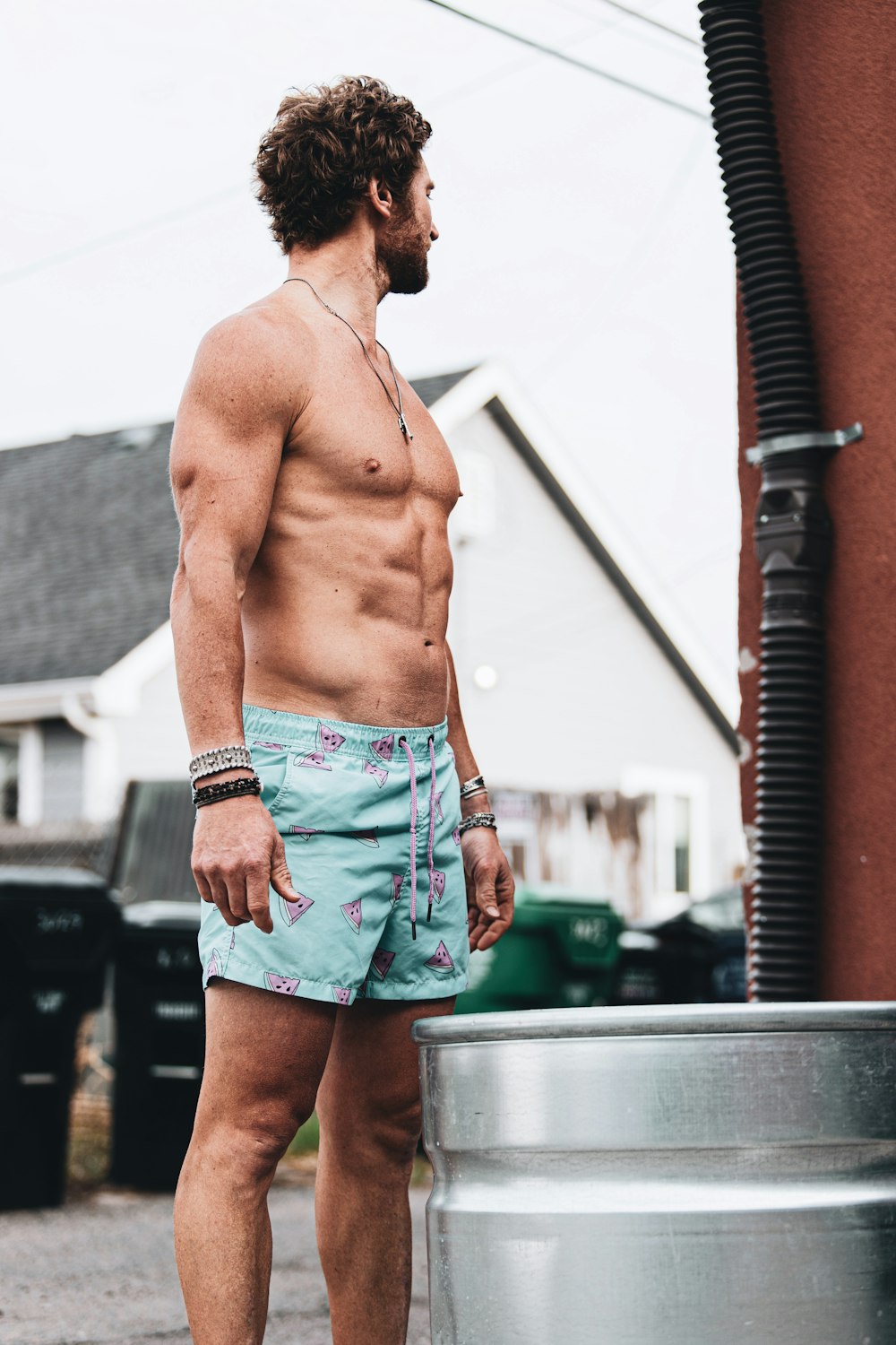 topless man in blue denim shorts standing near white wall during daytime