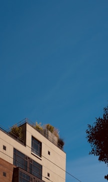 A modern residential building with large windows and greenery.