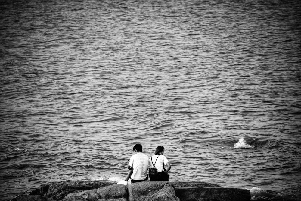바다의 바위에 앉아있는 2 명의 남자