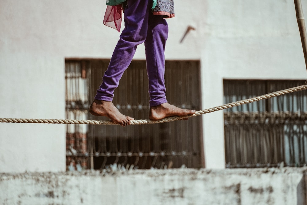 person in purple pants and pink jacket holding rope
