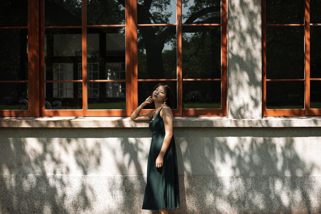 woman in black dress standing near window