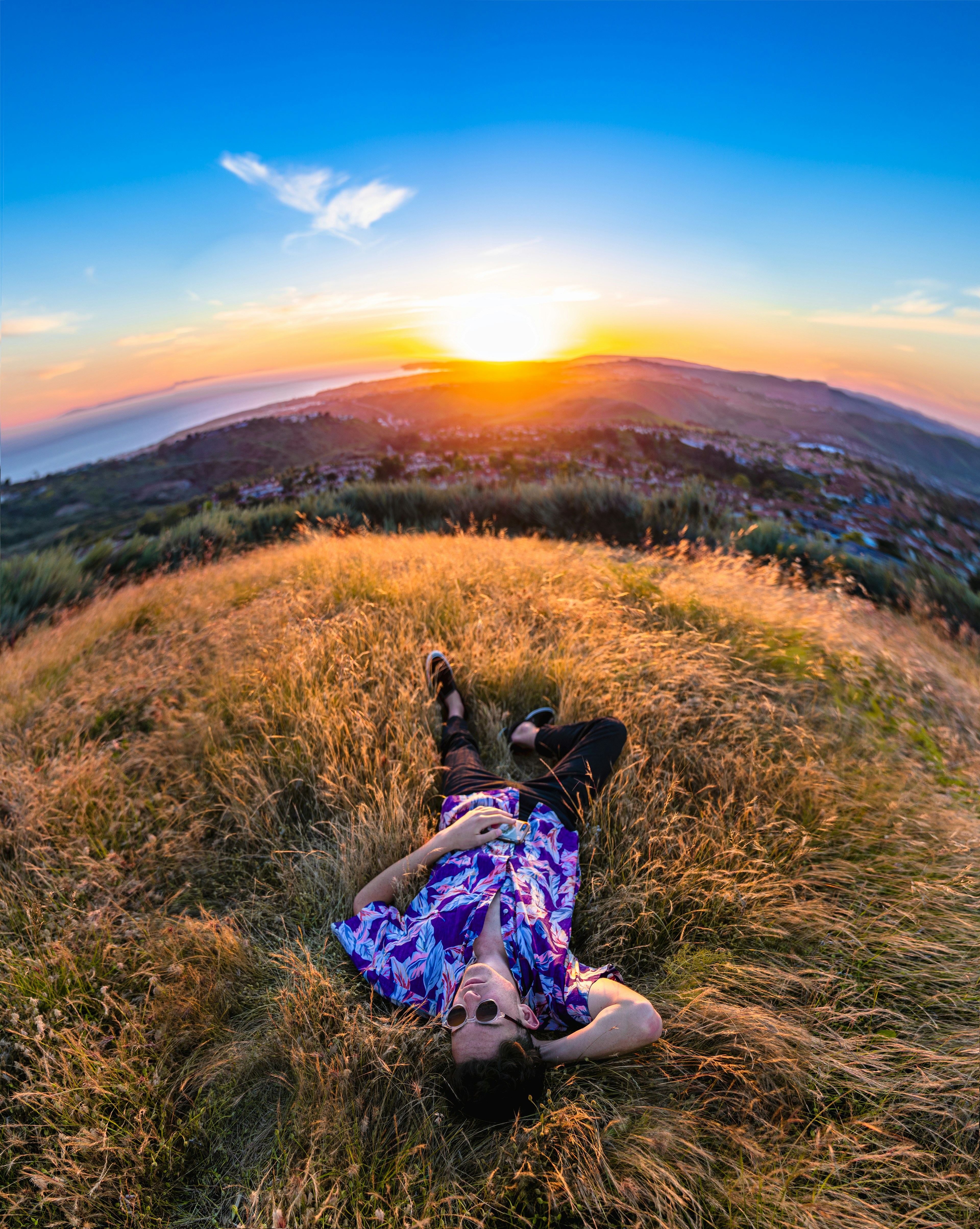 person in blue and white floral pants sitting on green grass during daytime