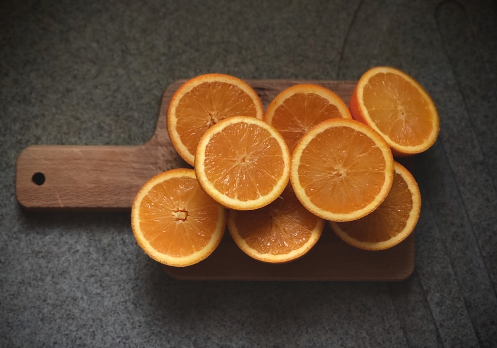 sliced orange fruit on brown wooden chopping board