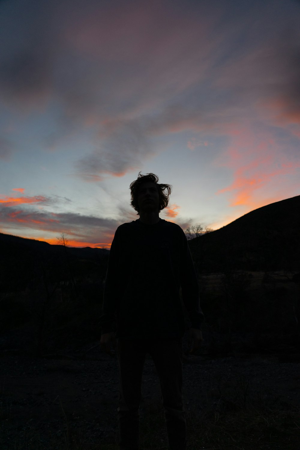 silhouette of man standing on hill during sunset