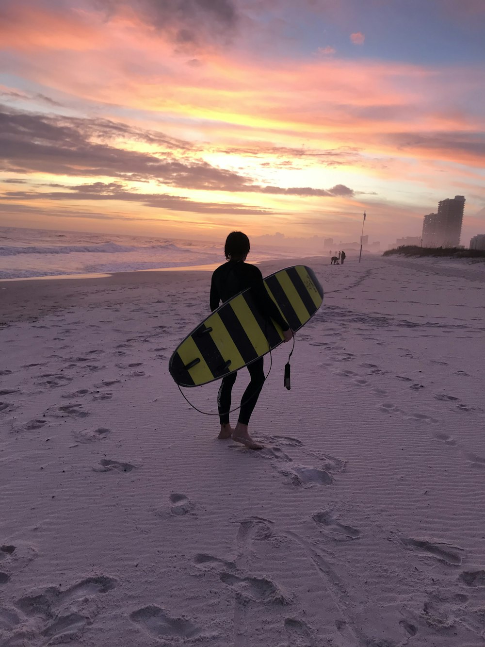 man in black and white checkered shirt holding white and black surfboard walking on beach during