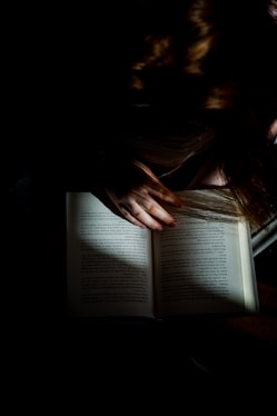 woman reading book on brown wooden table