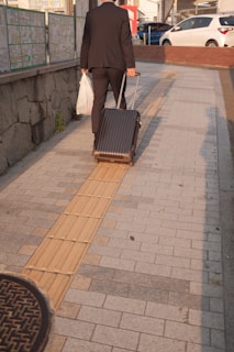 man in white shirt and black pants walking on sidewalk during daytime
