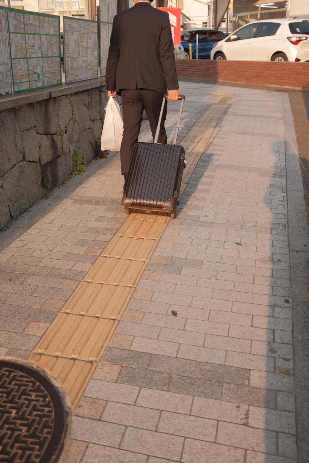 man in white shirt and black pants walking on sidewalk during daytime