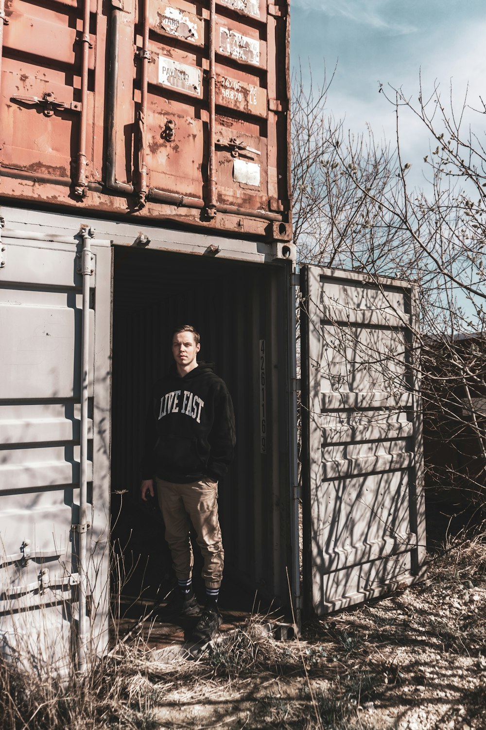 man in black and white crew neck t-shirt standing beside gray steel door during daytime