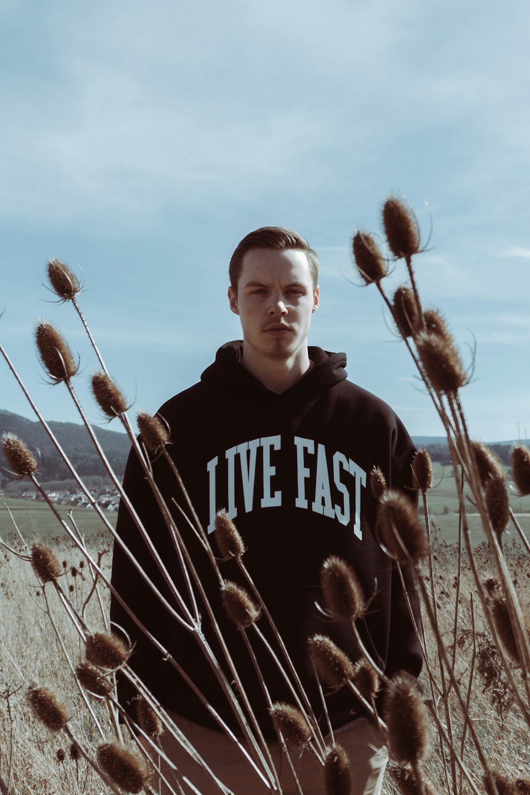 man in black and white pullover hoodie standing on brown grass field during daytime