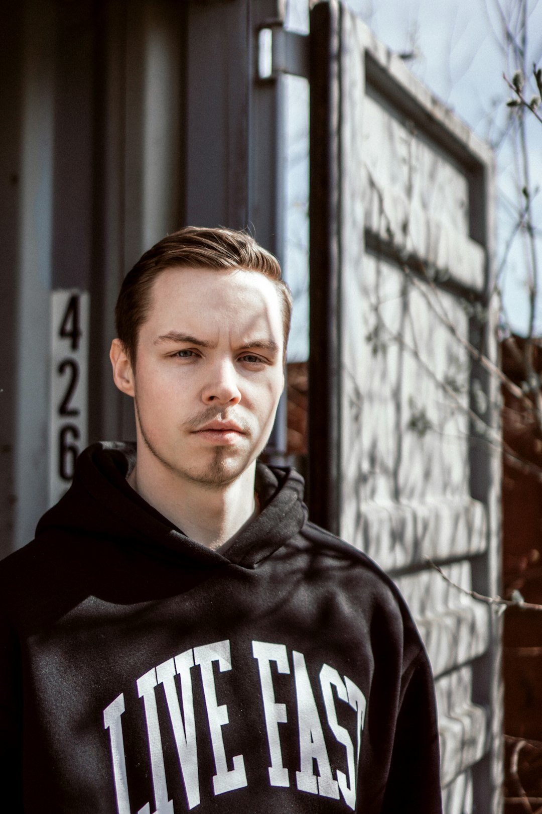 man in black and white pullover hoodie standing beside brown brick wall