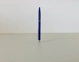 Close-up of a blue branded pen with a company logo on a white background.
