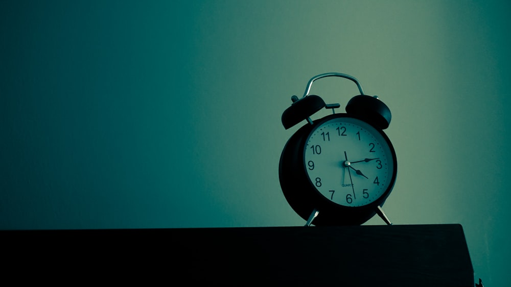 black and white analog alarm clock at 10 10