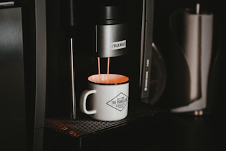 white ceramic mug on black and silver coffee maker