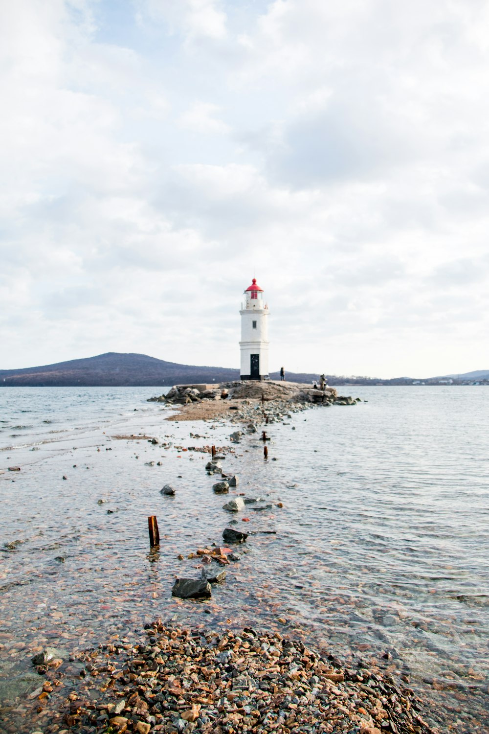 white lighthouse on body of water during daytime