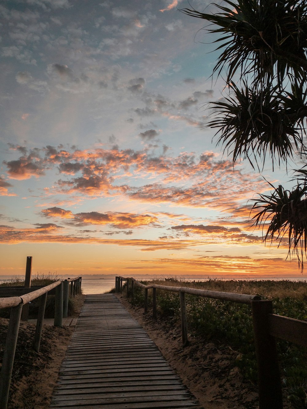 brown wooden bridge over the sea during sunset