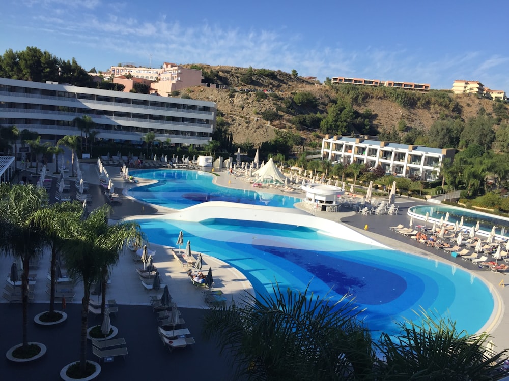 white and blue swimming pool near green trees and buildings during daytime