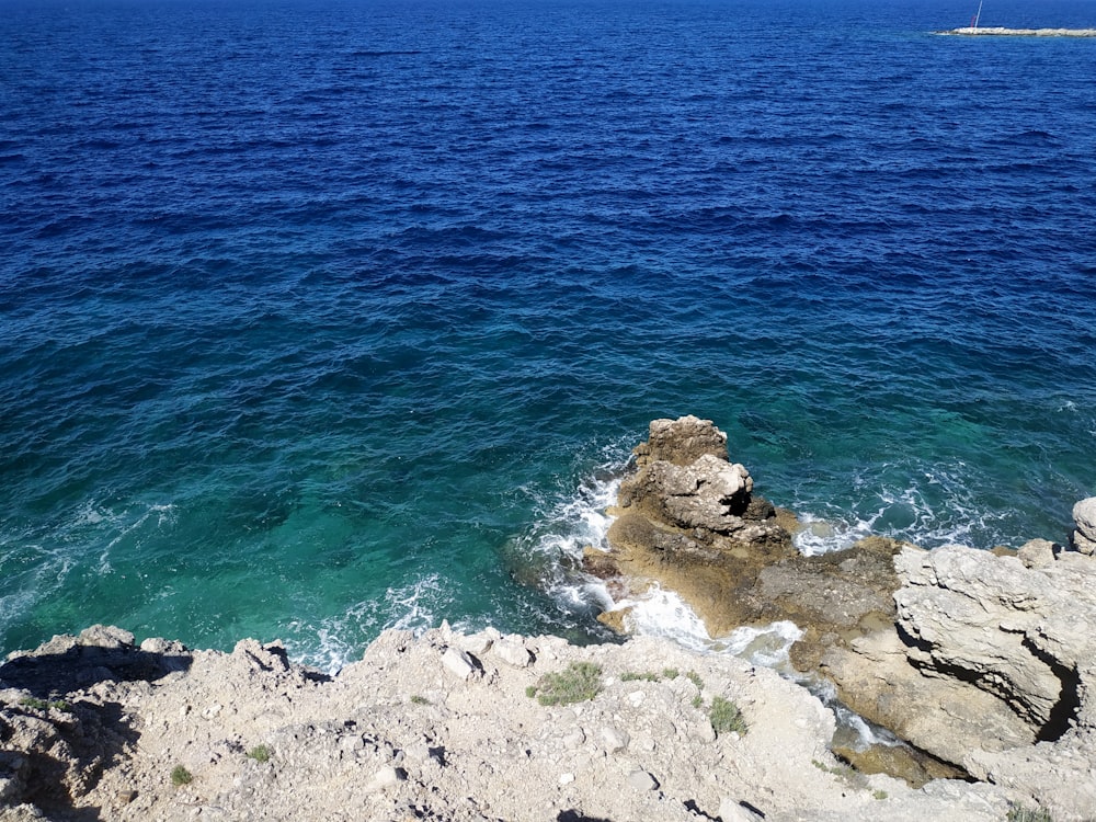 昼間の青い海のそばの茶色の岩層