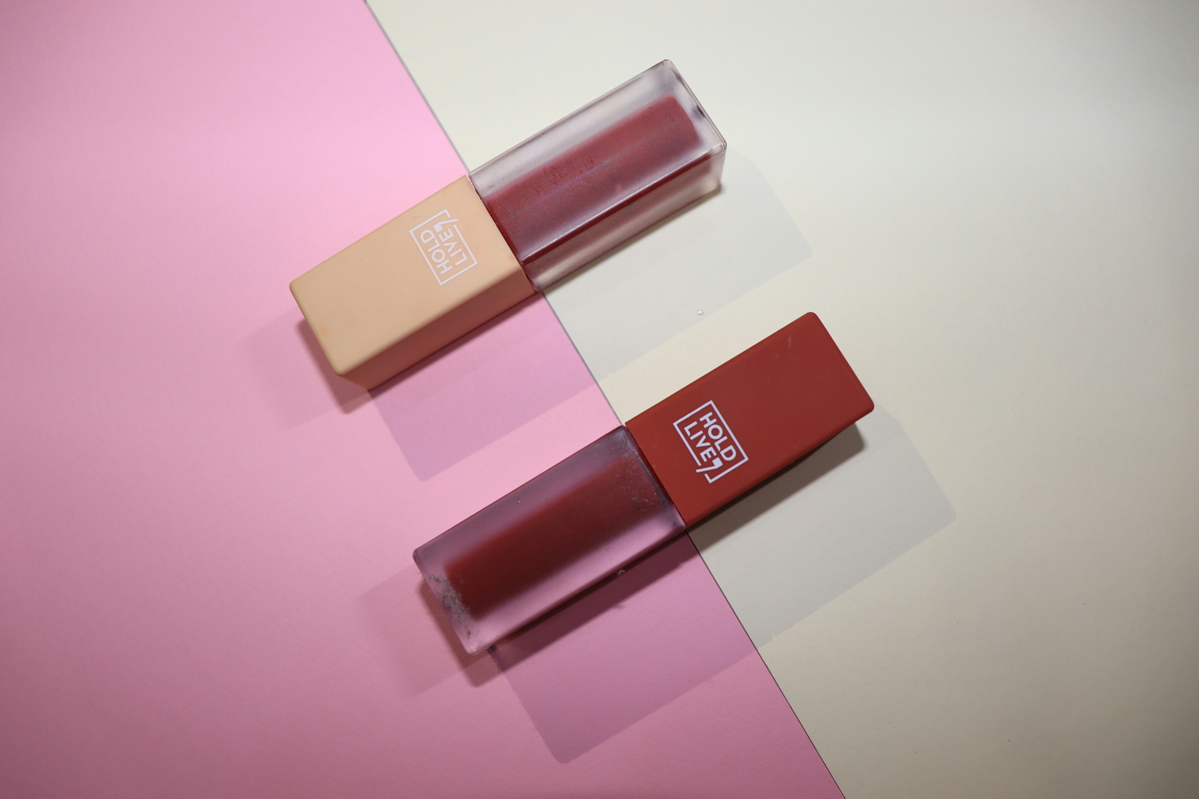 Luxury lipstick collection in deep berry and nude shades on soft pink background