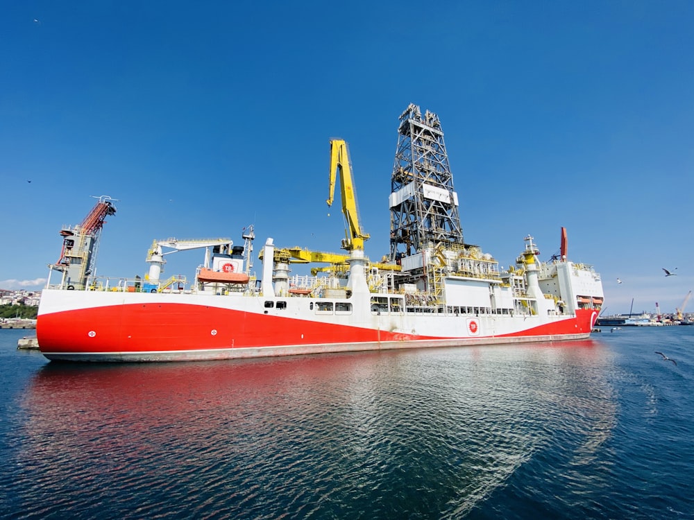 red and white ship on sea under blue sky during daytime