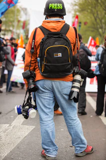 person in blue denim jeans and orange backpack walking on street during daytime