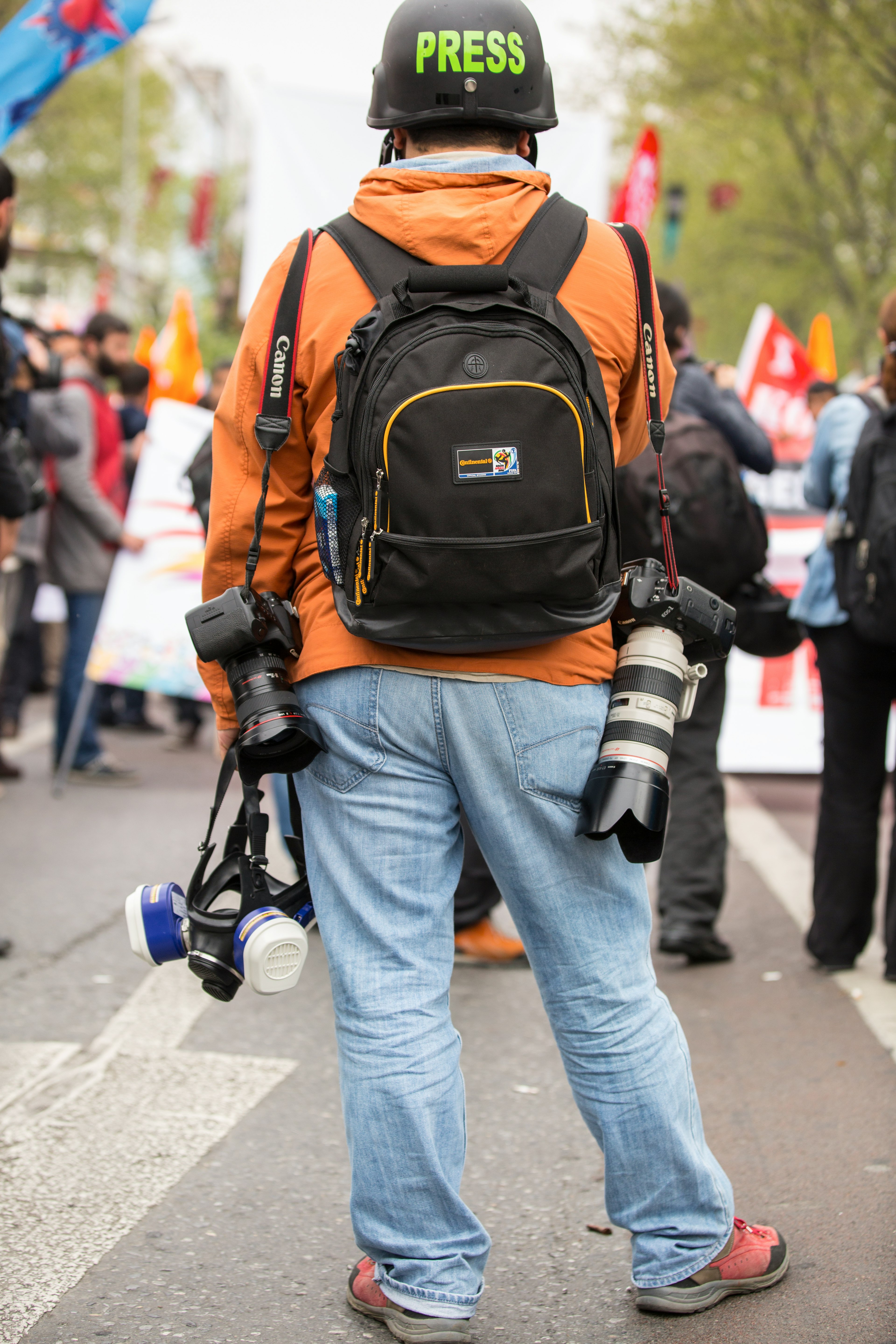 person in blue denim jeans and orange backpack walking on street during daytime