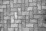 Interlocking pavers with a distinctive zigzag pattern cover a surface, showing signs of wear and some discoloration.