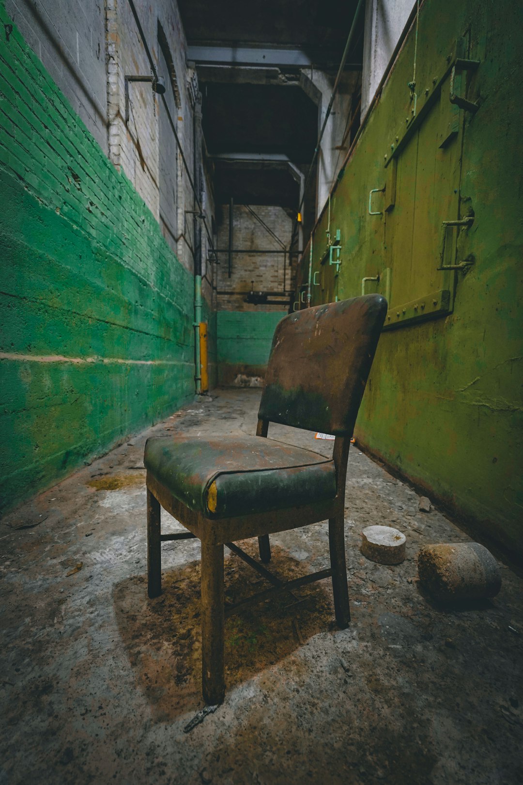 brown wooden armchair beside green wall
