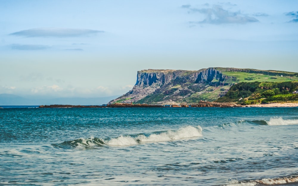 green and brown mountain beside sea during daytime