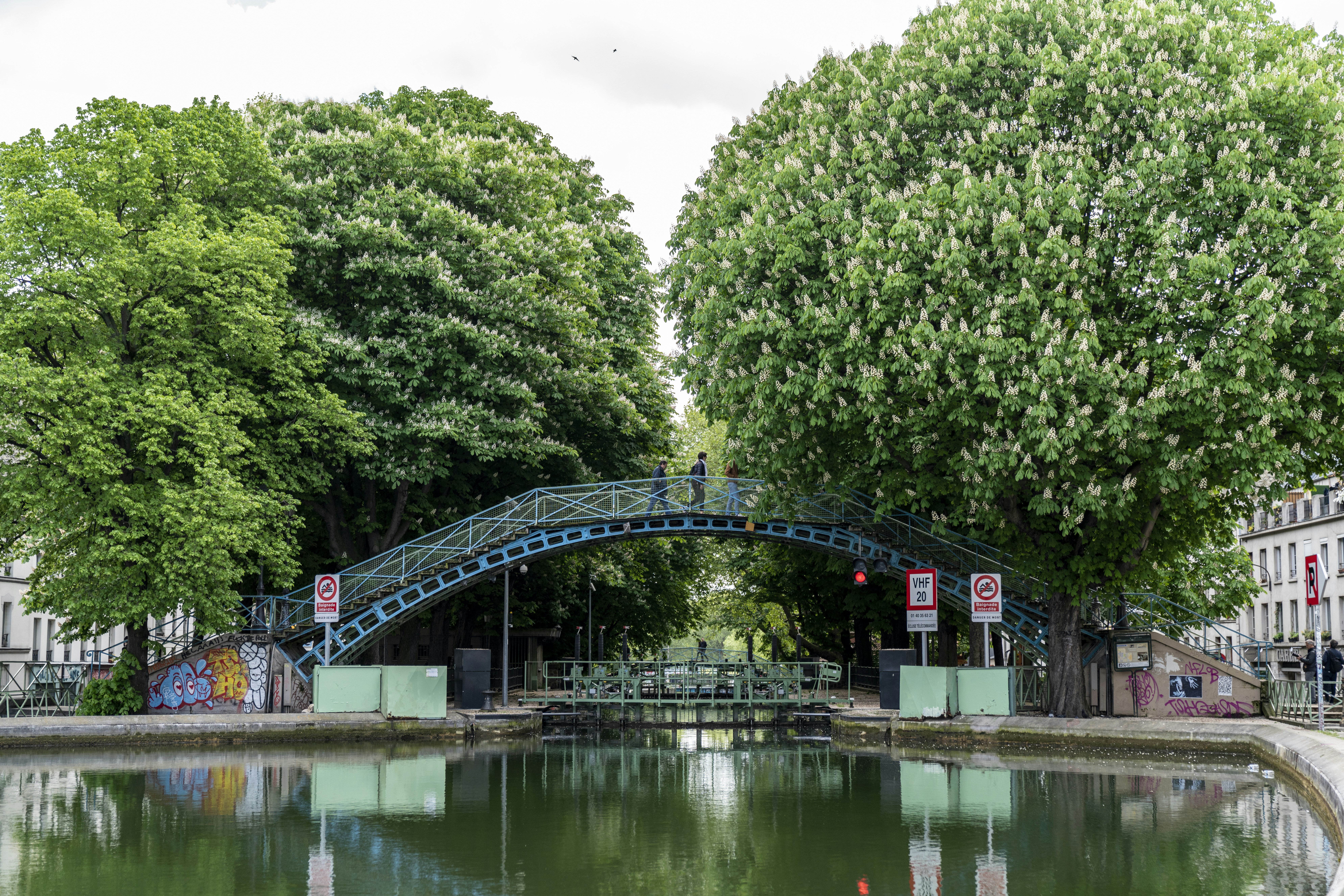 View of Canal Saint-Martin with street art and locals enjoying the scenery