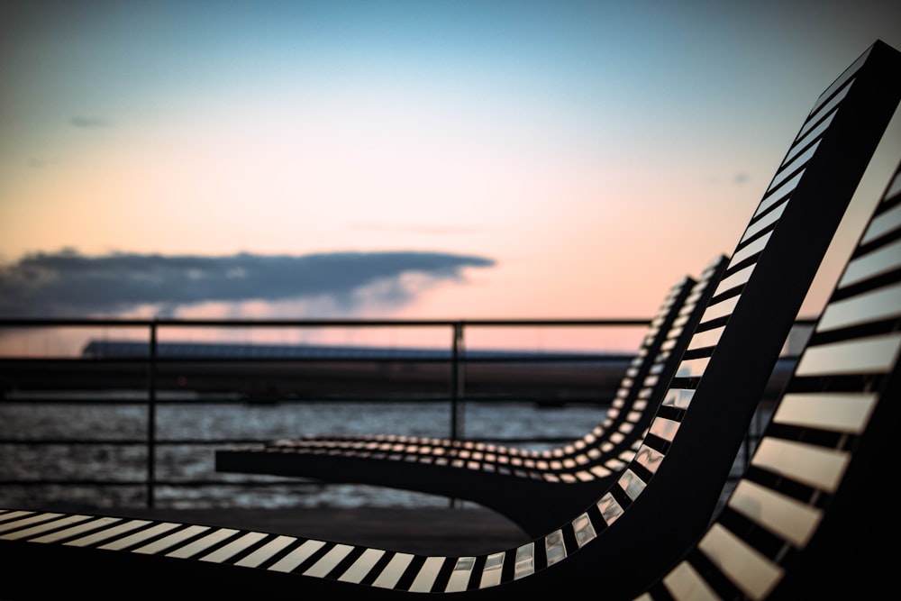 black metal bench near body of water during daytime