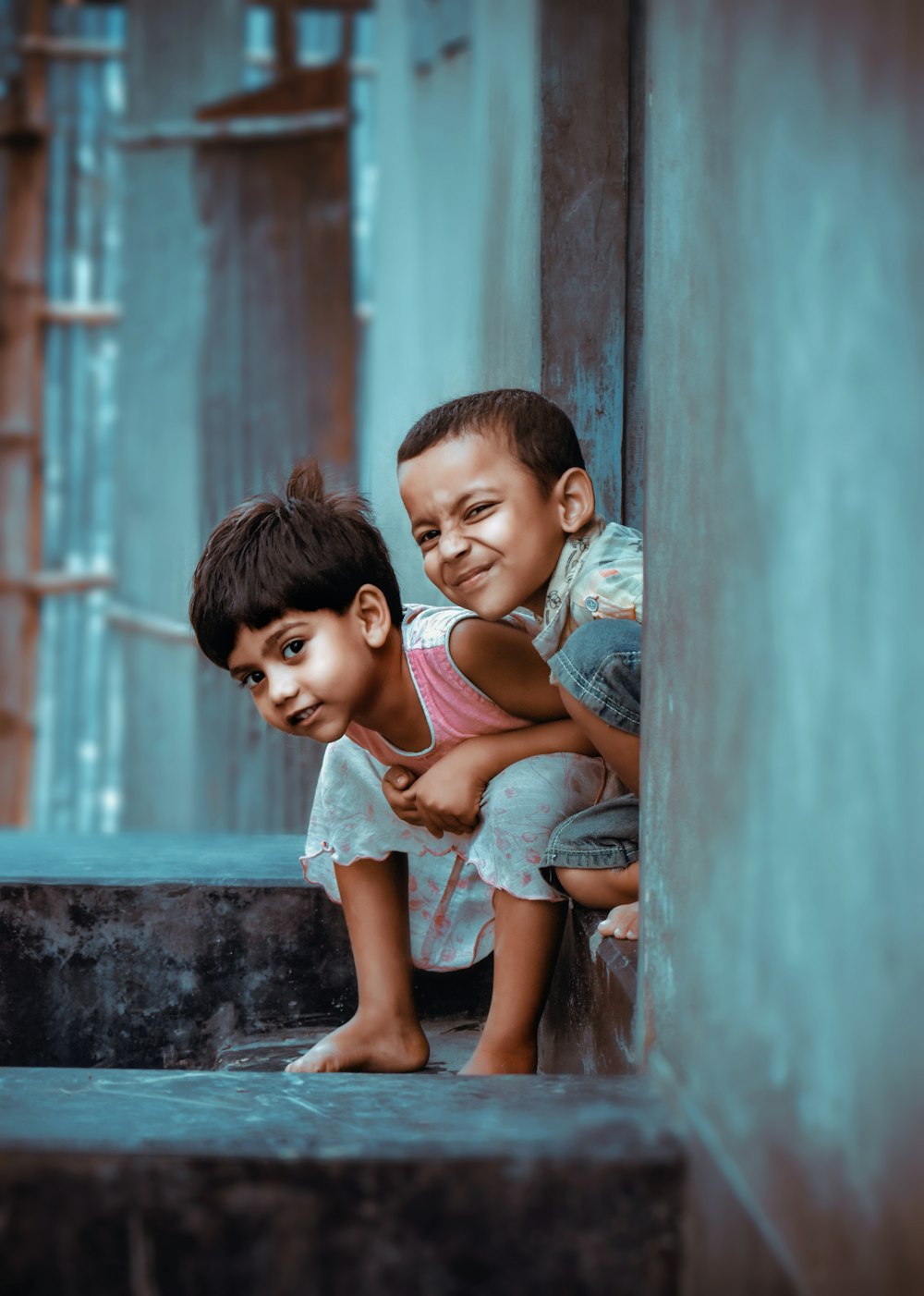 2 boys sitting on concrete wall during daytime