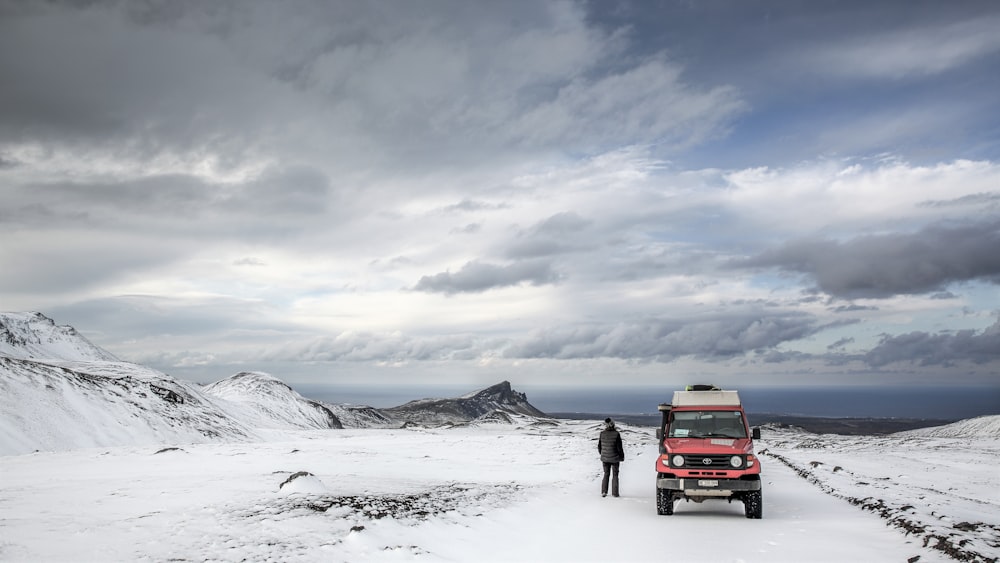 Roter SUV tagsüber auf schneebedecktem Boden unter bewölktem Himmel