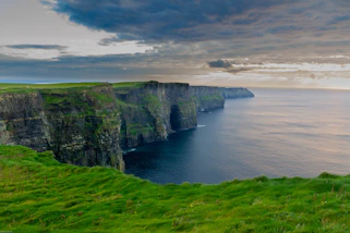 Campo de césped verde junto al mar en los acantilados de Moher en Irlanda