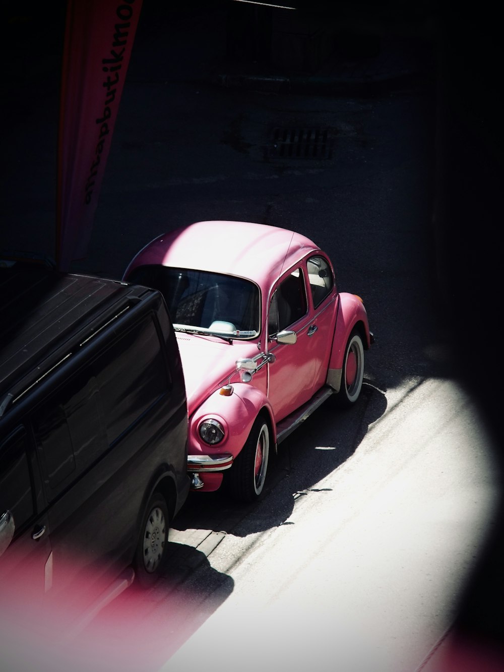 red volkswagen beetle parked beside black wall