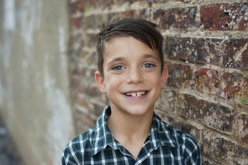 boy in blue and white plaid button up shirt smiling