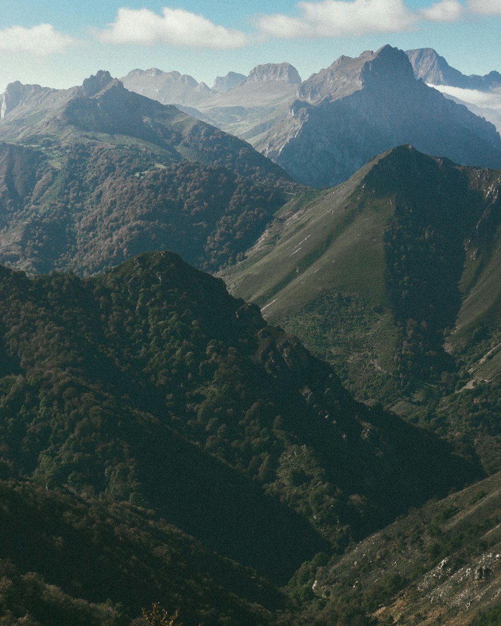 montañas verdes y marrones bajo el cielo blanco durante el día