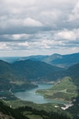 green mountains near lake under white clouds during daytime