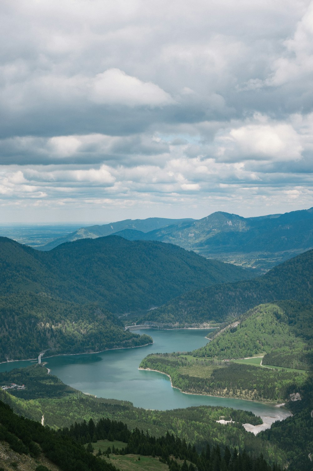 Grüne Berge in der Nähe des Sees tagsüber unter weißen Wolken