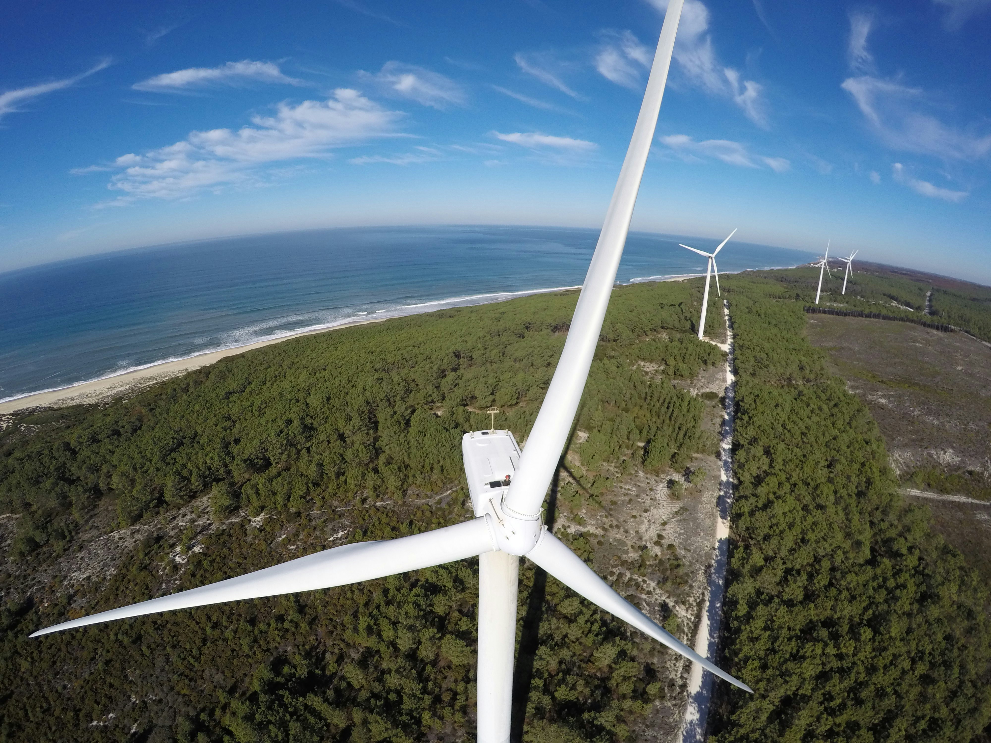 Weiße Windkraftanlage tagsüber auf grünem Rasenplatz unter blauem Himmel